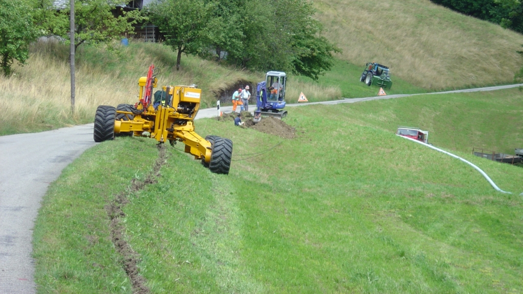 ein Bulldozer auf einem grasbewachsenen Hügel die für Abwasserrohre bauen.