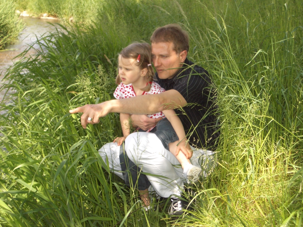 Direktor Stefan Hasler zeigt seiner kleinen Tochter etwas am Flussufer.
