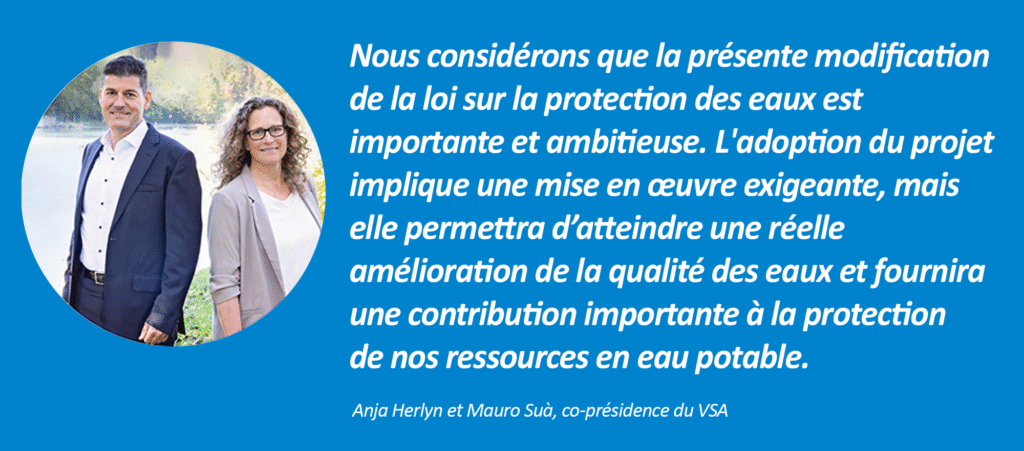 Zwei Personen stehen im Freien am Ufer eines Sees. Neben ihnen zeigt eine blaue Tafel ein französisches Zitat über die Bedeutung des Wasserschutzgesetzes, das Anja Herlyn und Mauro Suà zugeschrieben wird.