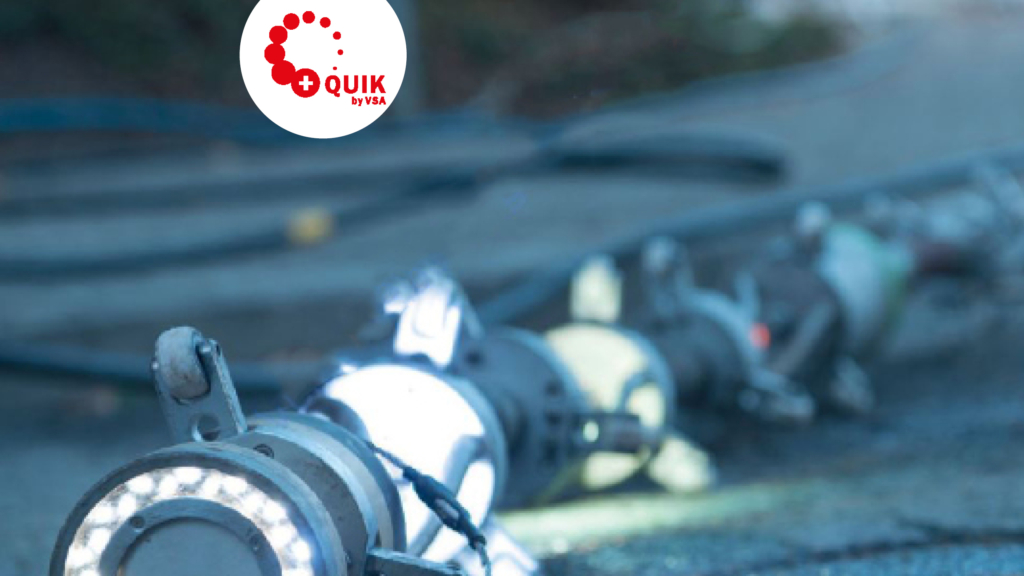 Eine Nahaufnahme von Industrieanlagen mit Kabeln auf dem Boden; das Quik by TIVA-Logo erscheint in der oberen linken Ecke.