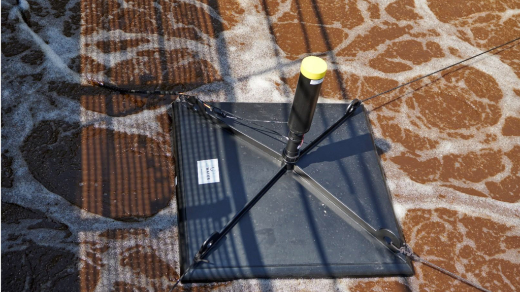 Luftaufnahme eines Gebäudes mit Solarmodulen auf dem Dach neben einer Baustelle mit Betonfundamenten und Baumaterialien.